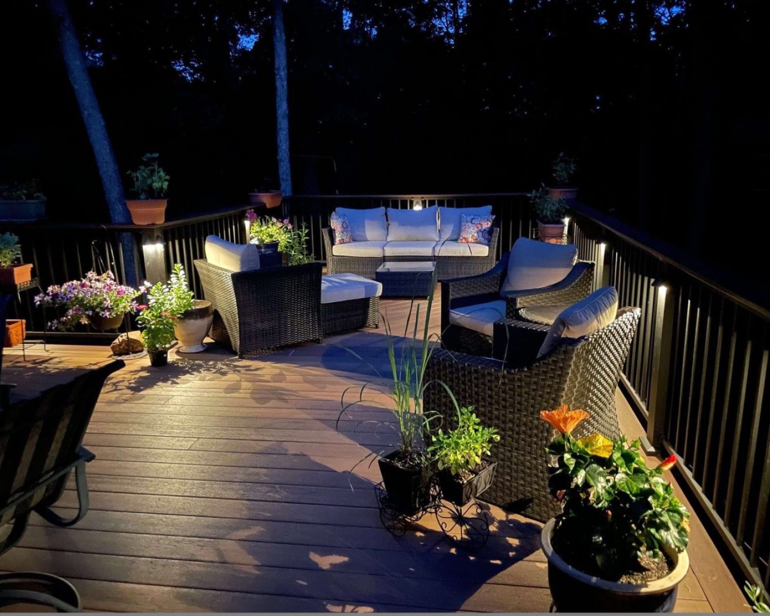 A photo of a back porch during night time with lights on the side of the beams giving light to the porch