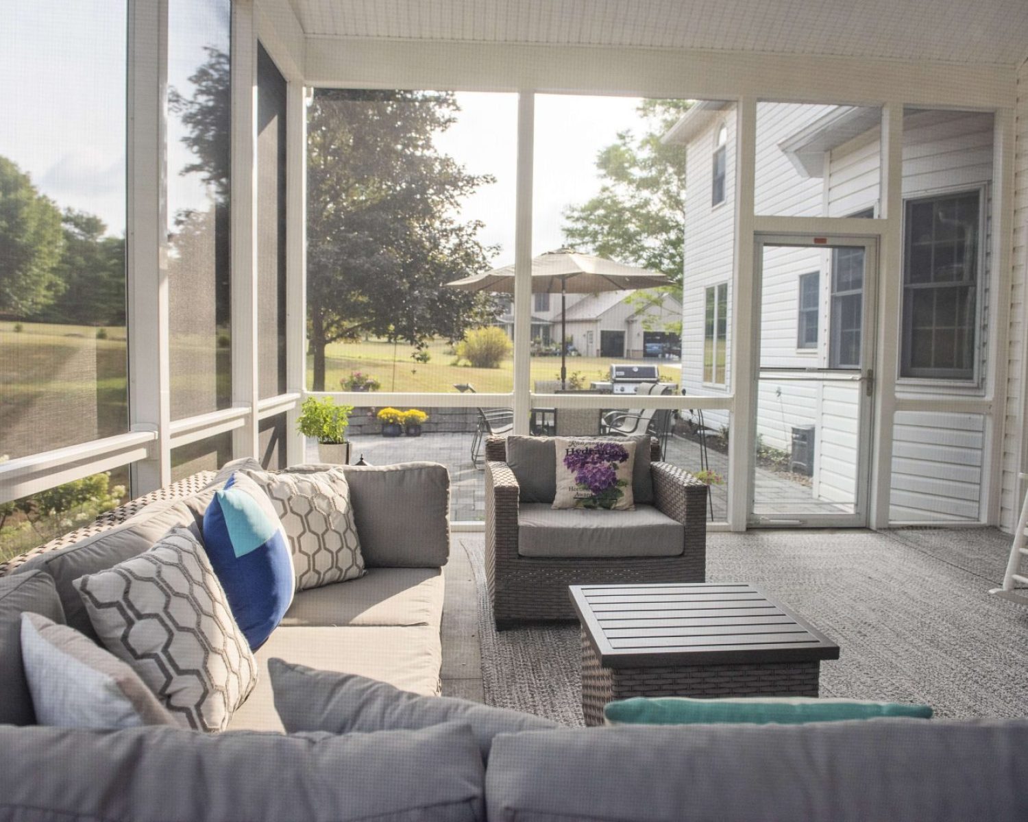A screened in porch with couches and a mini table for resting drinks